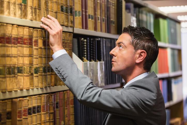 A male law clerk picking a book in the law library after completing his law clerk training