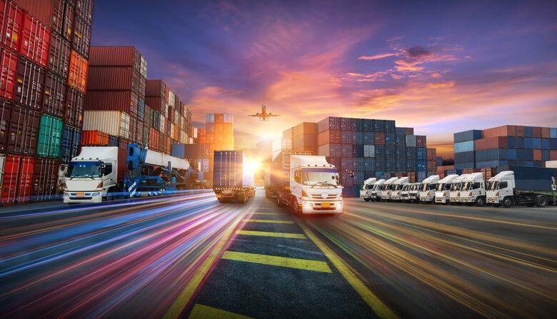 Two trucks passing each other at sunrise in a  work yard of a logistics training grad.