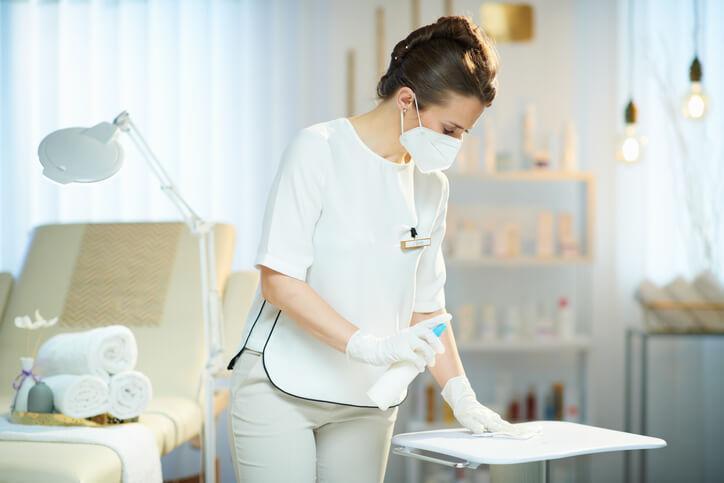 Medical esthetician cleaning a treatment station according to infection control standards Medical esthetician cleaning a treatment station according to infection control standards
