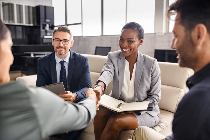 A female business management training grad shaking hands with an employer in an interview