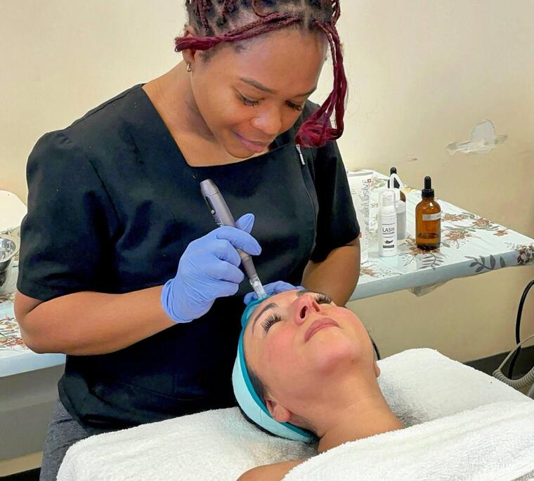 A student performs a medical esthetics facial treatment using a handheld device on a client.