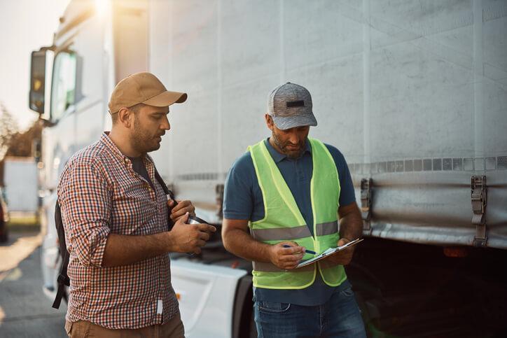 A male dispatcher standing close to a delivery truck after supply chain and logistics training.