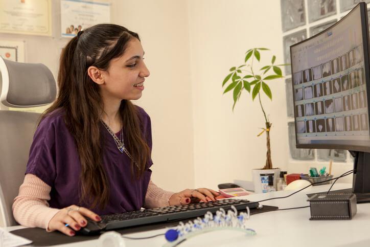 A career college graduate doing record-keeping tasks on a computer