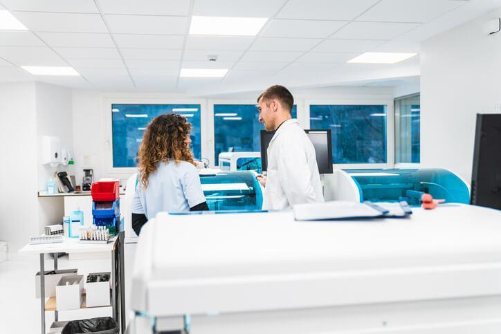 A male pharmacy technician student watching a female pharmacy technician work during pharmacy technician training