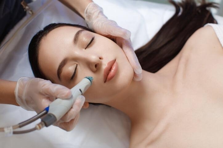 A female medical esthetician administering laser skin treatment after completing her medical esthetician training