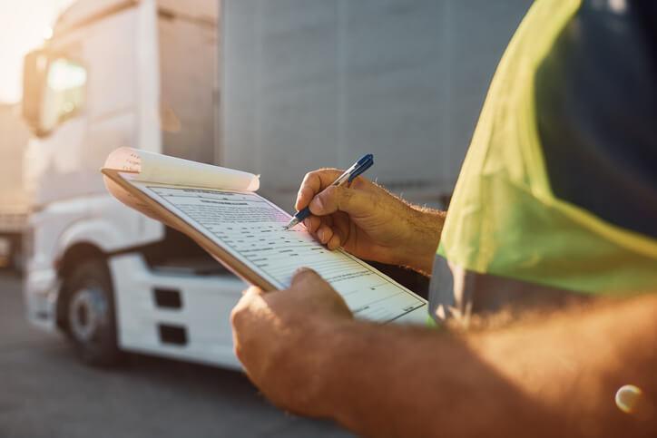 A male dispatcher going through a checklist after supply chain and logistics training.