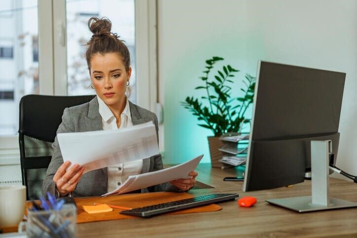 A female paralegal reading a report in her office after completing her paralegal program.