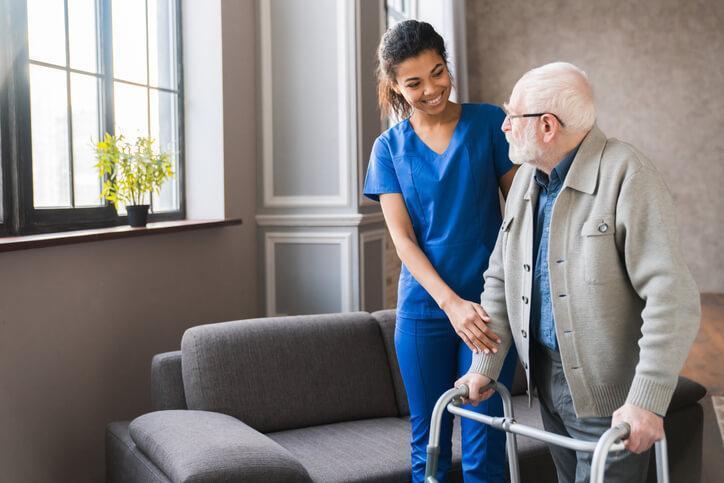 A PSW course grad helping an elderly client with a walker