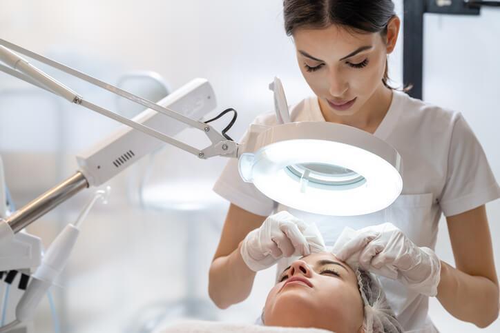 A medical esthetician performing a facial in a clinical setting