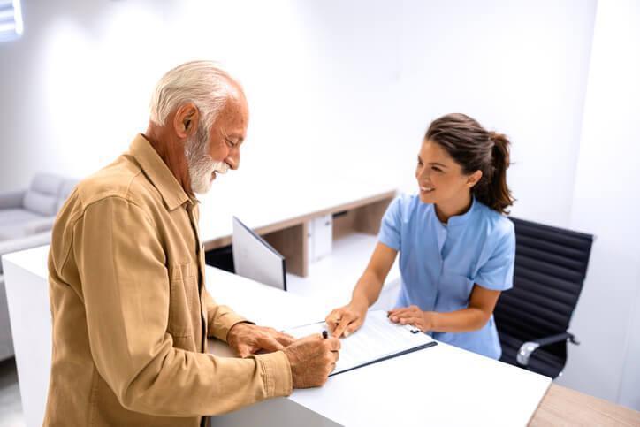 A friendly female medical office assistant interacting with a male patient