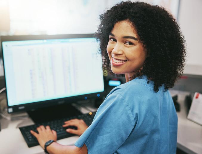 A career college graduate working at a computer desk