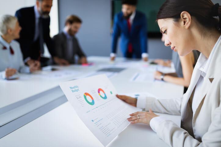 An entry-level business professional reviewing KPI reports during a team meeting