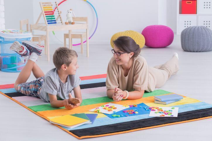 A female early childcare assistant interacting with a male pupil in a classroom