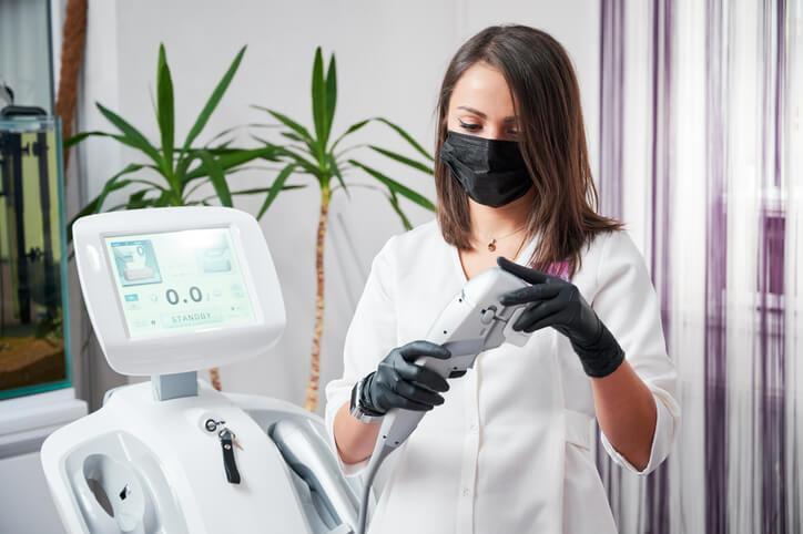 Female medical esthetician working with a cosmetology device after completing her medical esthetician training