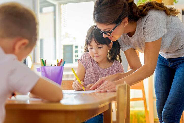 early childcare assistant helping a student with her writing