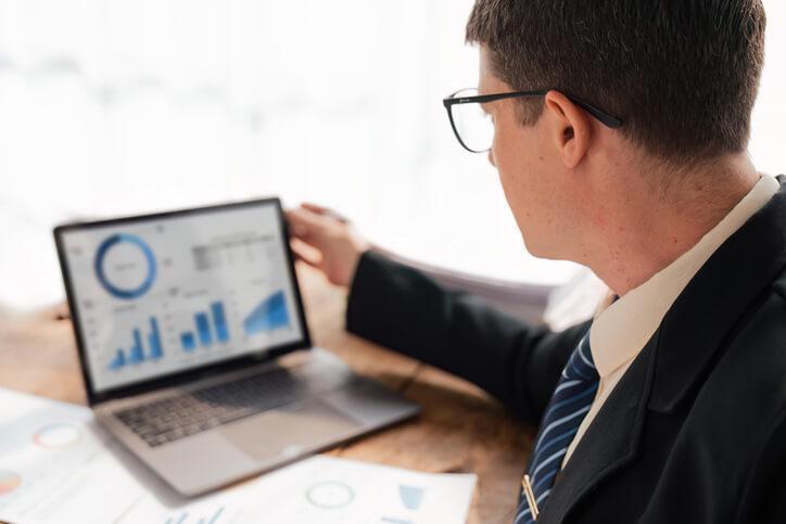 A business management graduate analyzing sales performance data on a laptop