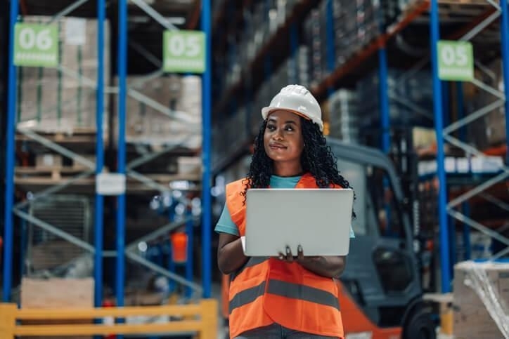 A smiling supply chain and logistics grad working in a warehouse