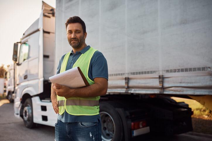 A male dispatcher communicating with a truck driver after supply chain and logistics training.