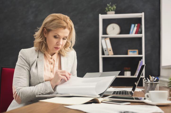 A busy female law clerk reading legal documents in an office after completing her law clerk training