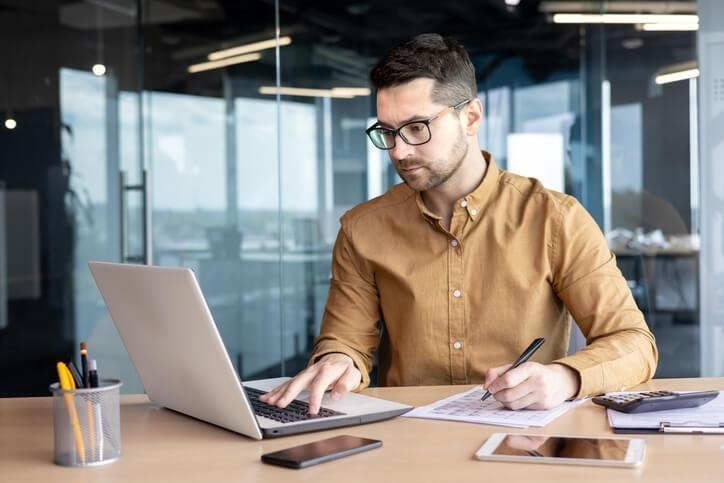 A smiling accounting administration diploma holder doing paperwork at a desk