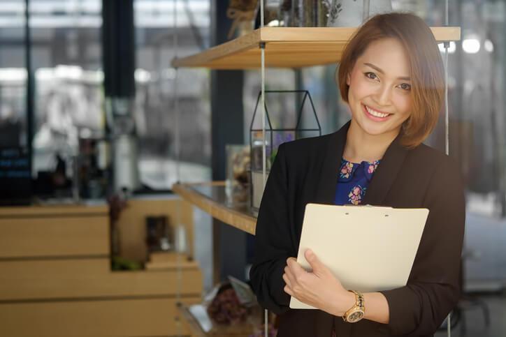 A smiling female law clerk holding a notepad in an office after completing her law clerk diploma program