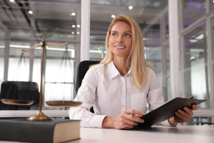 A smiling female law clerk holding legal documents in a law office