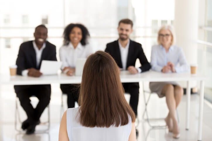 A panel of four people interviews a female business management candidate