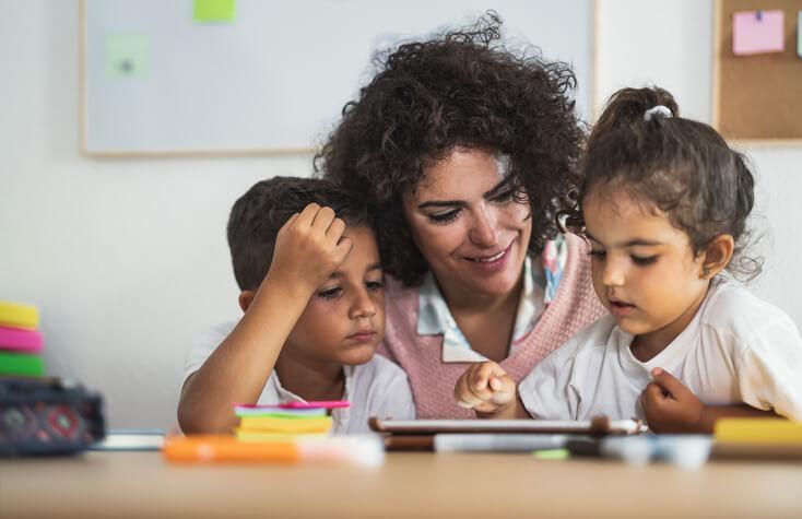 early childcare assistant using a tablet to teach children