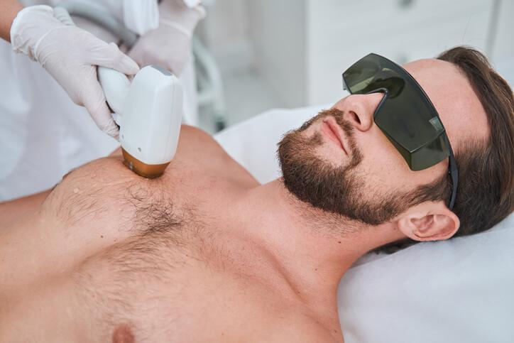 A medical esthetician using a laser device on a client in a clinic