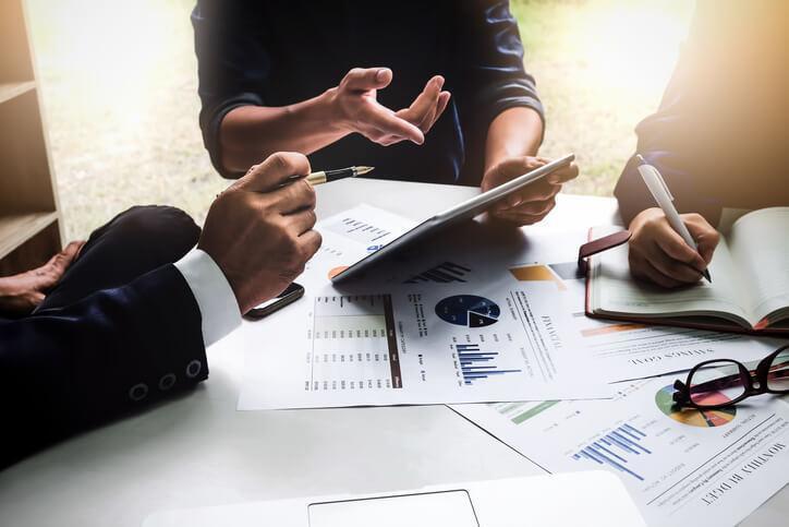 A team of logistics training grads conducting and discussing market research at a table.