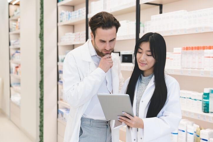 A pharmacy technician reviewing prescriptions with a pharmacist assistant, showing one of the key responsibilities of a pharmacy assistant