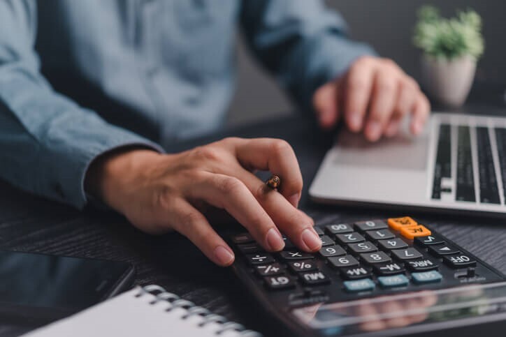 Male payroll clerk working with a calculator after accounting and payroll training