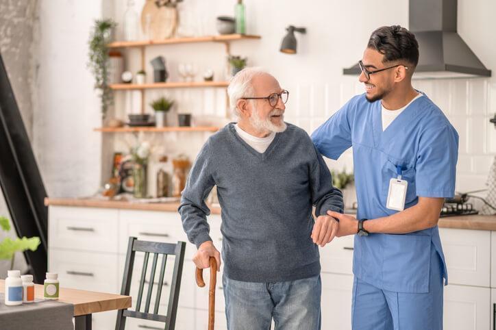 A PSW course grad assisting an elderly client in his home