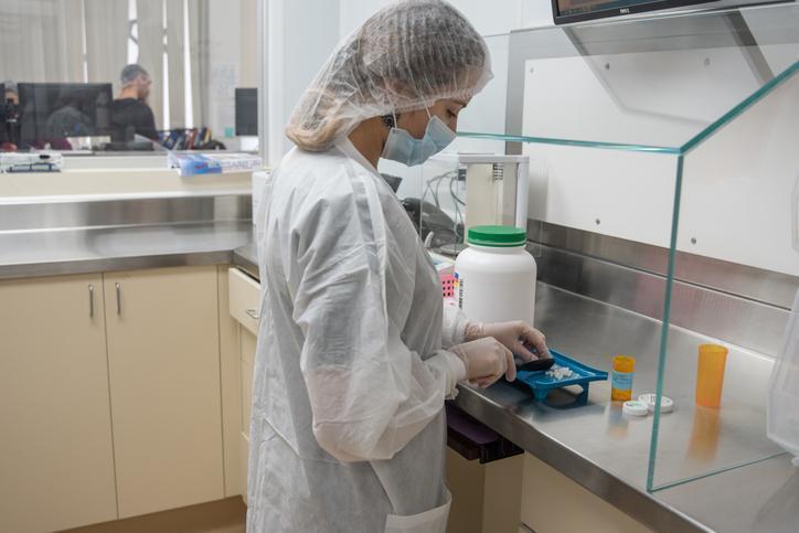 A hospital pharmacy technician preparing medications in a sterile workspace